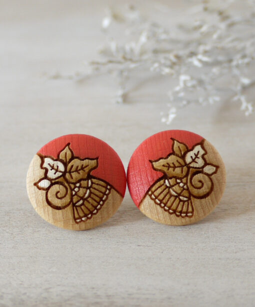 detailed wooden earrings in coral color large on background