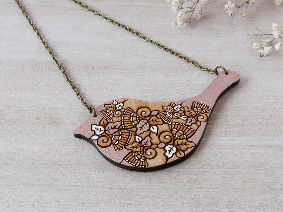 bird rose gold wooden necklace on background